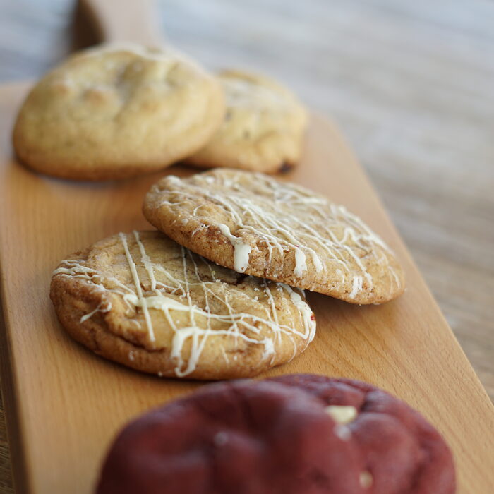 Dikke, chunky cookies met witte chocolade drizzle op een houten plank, vers gebakken door Nanne's Cookies & Brownies in Katwijk